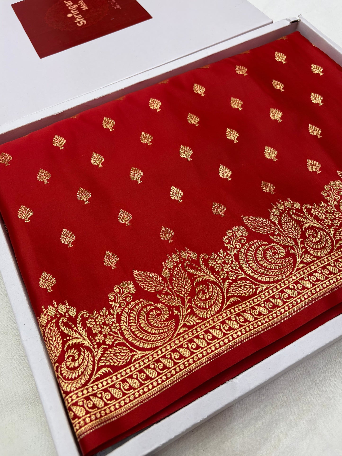 Red fabric with gold patterns in a white box