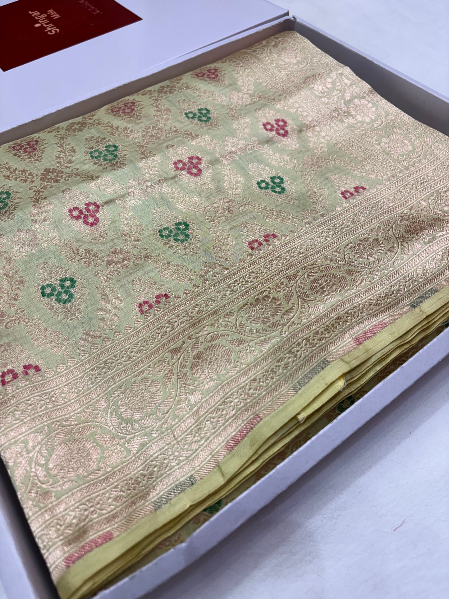 Close-up of a patterned fabric with red and green designs on a white background