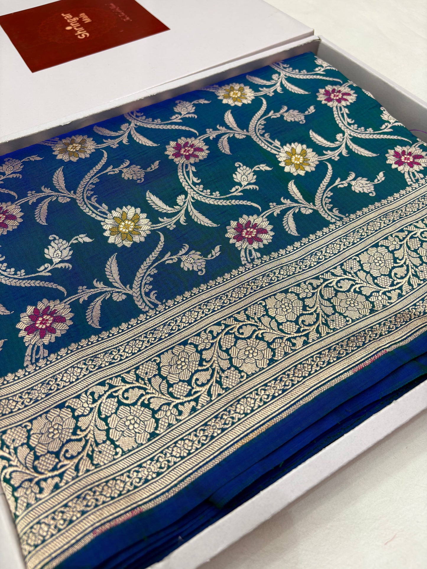 Blue saree with floral patterns on a white box
