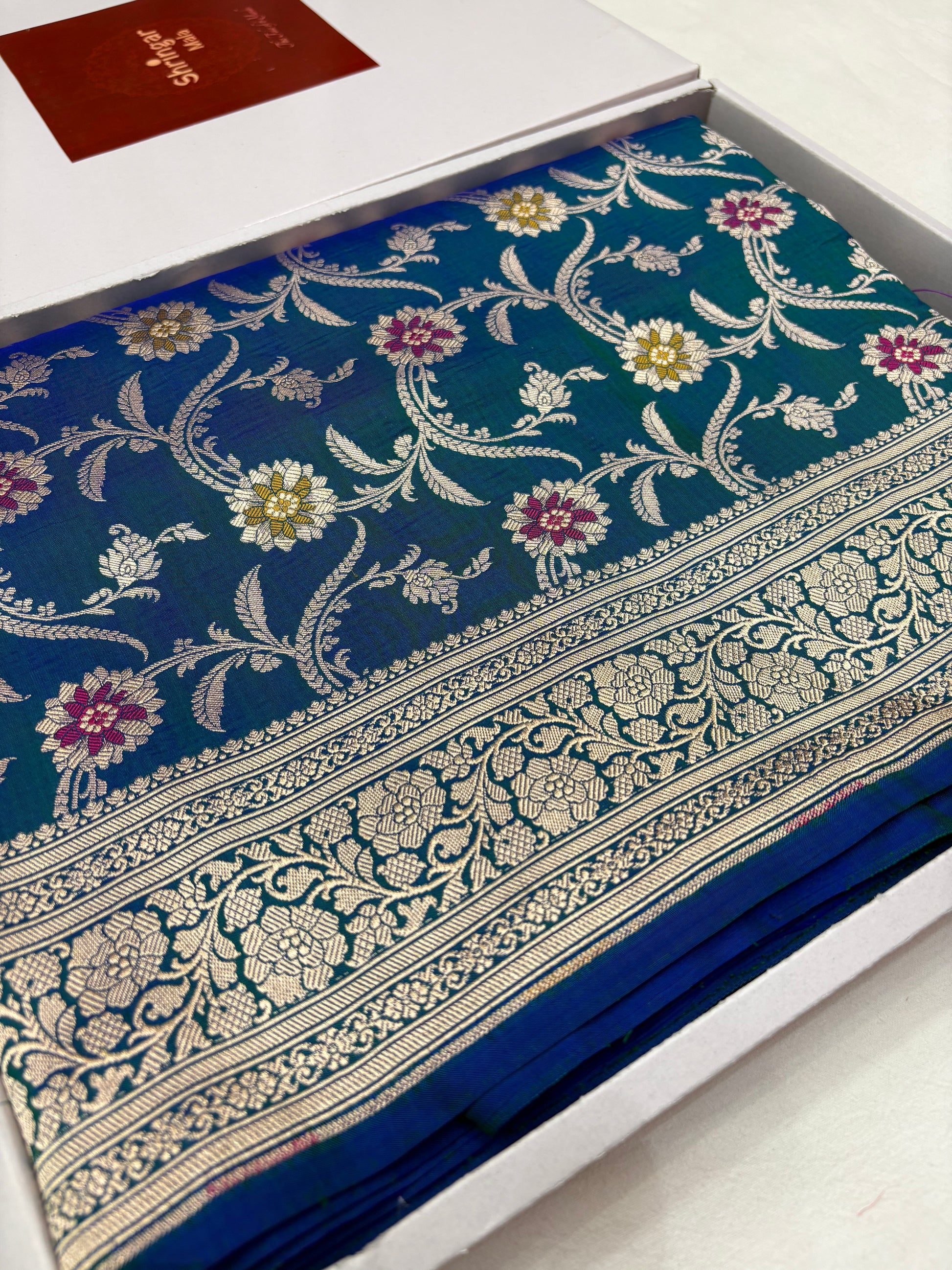 Blue saree with floral patterns on a white box