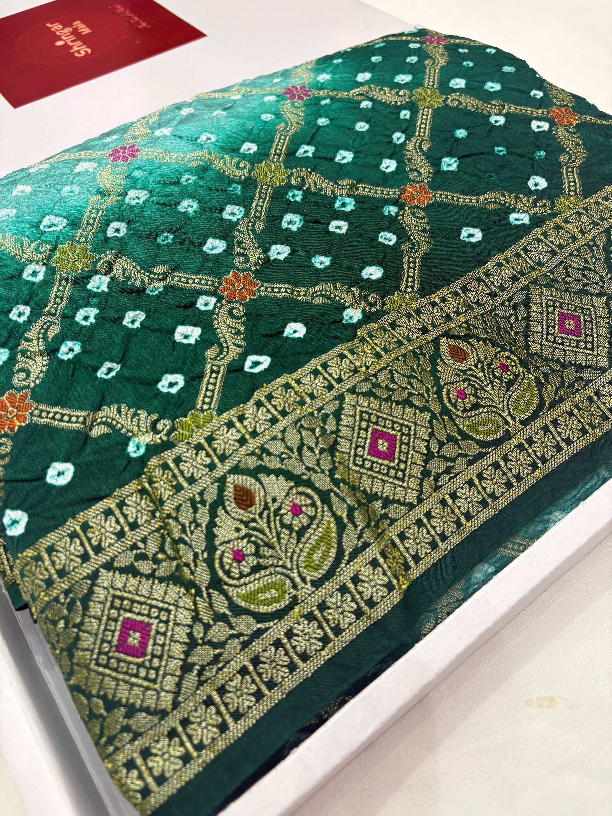 Green embroidered fabric with intricate patterns on a white background