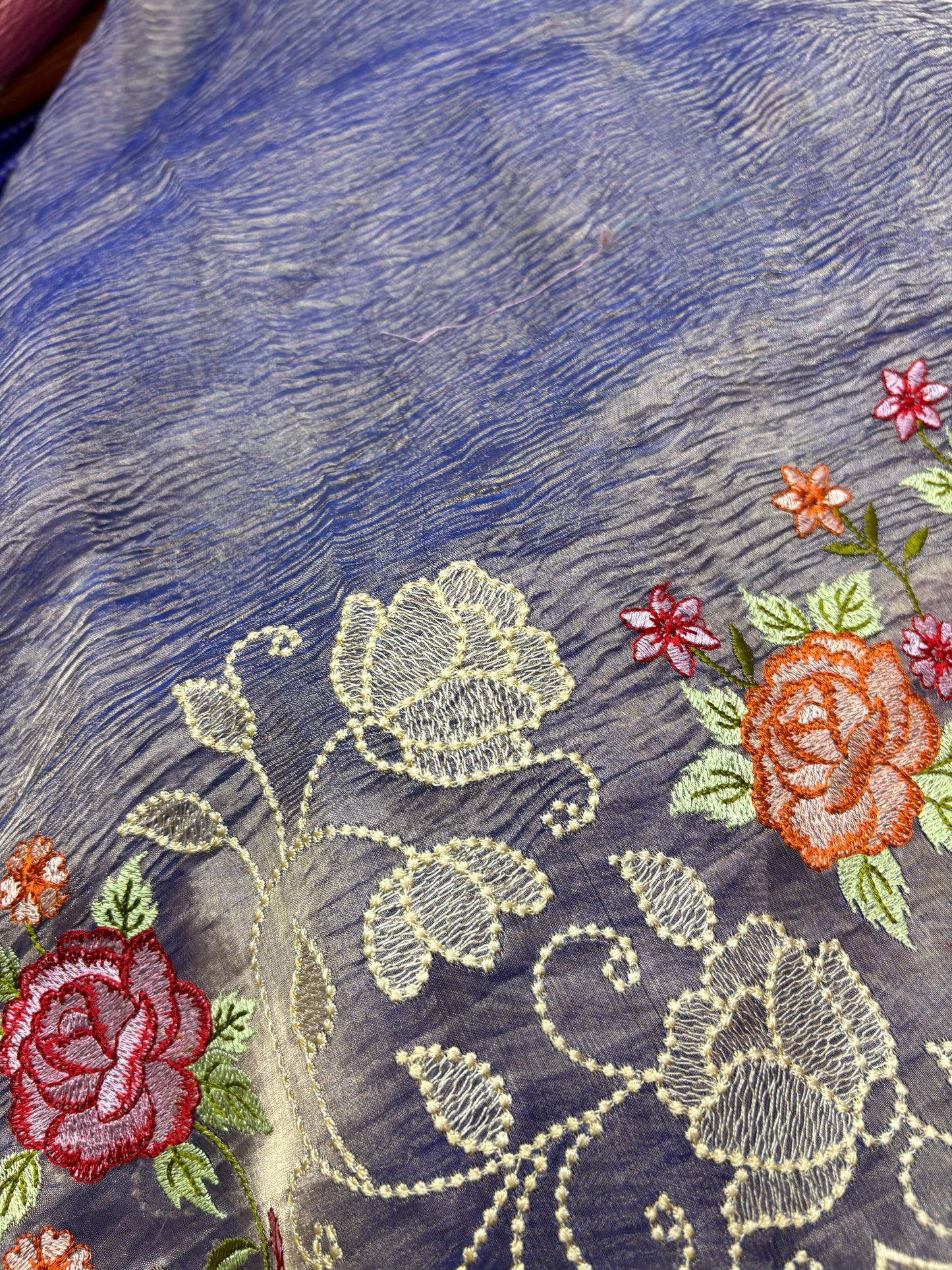 Close-up of embroidered fabric with floral designs on a blue background