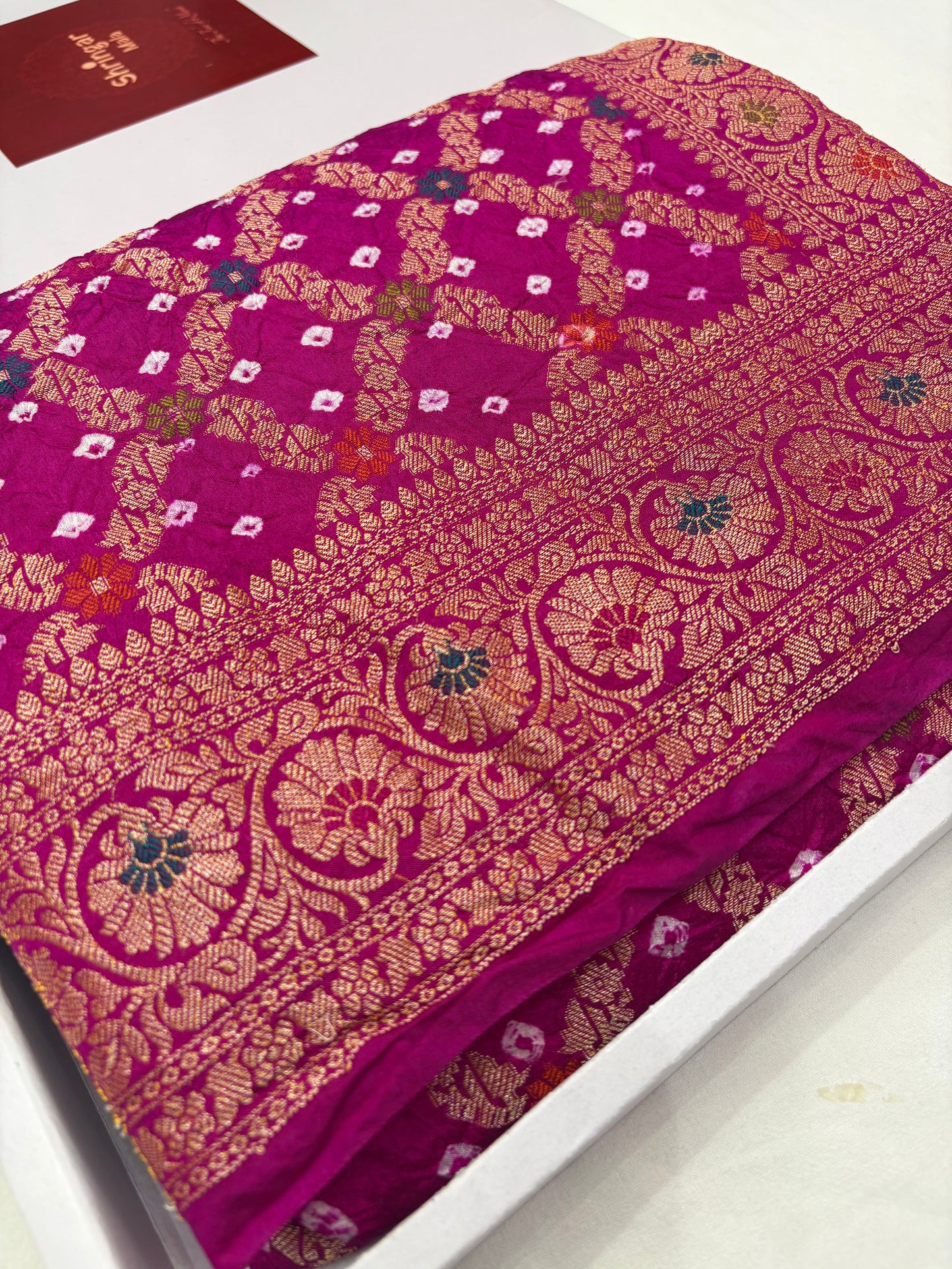 Purple fabric with gold and white floral patterns on a white background